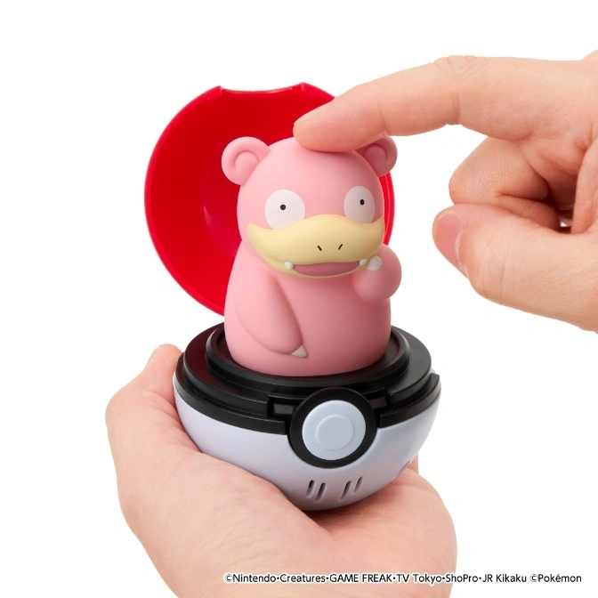 Slowpoke toy in a Poké Ball being pressed by a finger. Red lid is open.