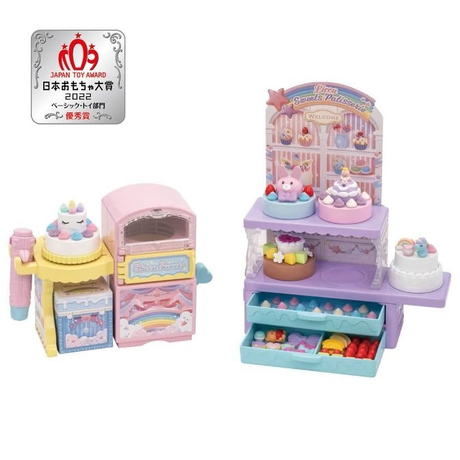 Pastel toy bakery set with oven, display shelves, cakes, and accessories.