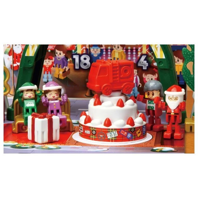  Toy cake with a fire truck on top, surrounded by toy figures and a gift box.