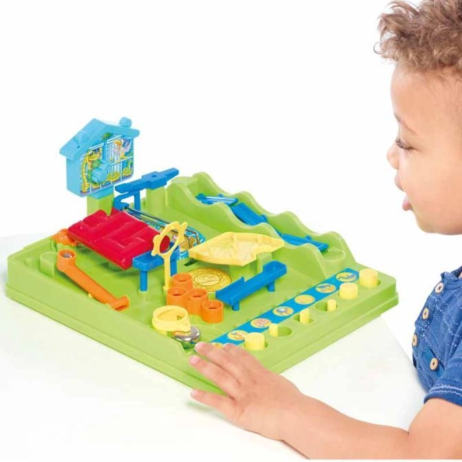 A child plays with a green mousetrap-style board game with colorful obstacles and a mouse figure.