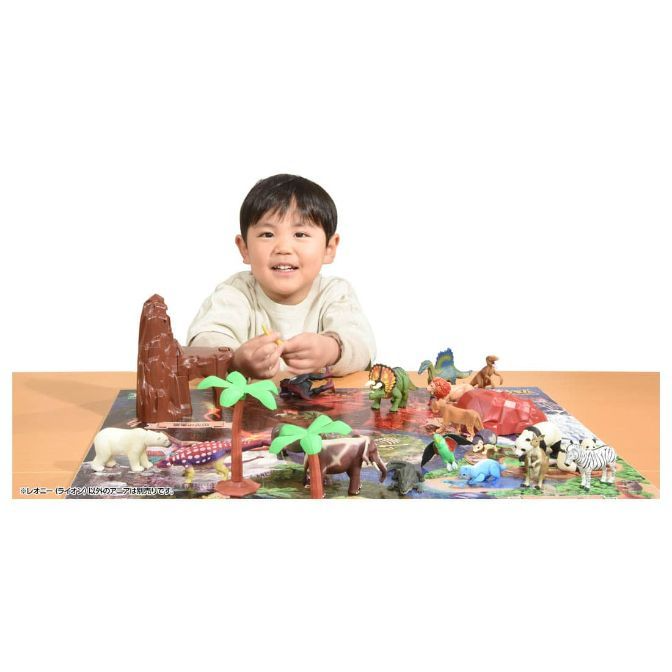  Child playing with animal figurines and a playset featuring trees and a rock formation.