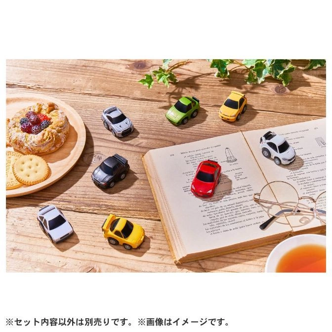  Collection of colorful toy cars on a book with pastries and tea.