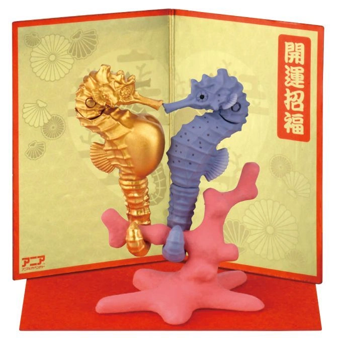 Gold and blue seahorse toys on pink coral against a Japanese-themed backdrop.