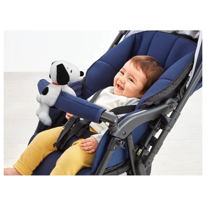  Baby in stroller with Snoopy plush toy attached to the safety bar.
