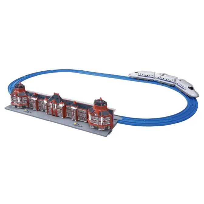  A toy train set with a blue track, a white bullet train, and a building that resembles a train station.